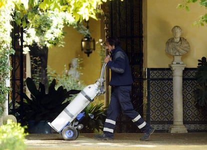 Un operario lleva varias botellas de oxígeno al Palacio de las Dueñas, residencia sevillana de Cayetana Fitz-James Stuart, duquesa de Alba