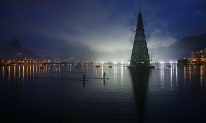 Dos hombres montan en un stand up paddle al lado de un árbol de Navidad de 85 metros de altura situado en el parque Cantagalo en Río de Janeiro (Brasil), 1 de diciembre de 2013.