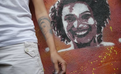 A viúva de Marielle Franco, Mônica Benício, ao lado de grafite da vereadora assassinada.