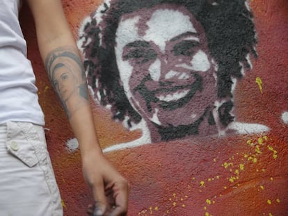 A viúva de Marielle Franco, Mônica Benício, ao lado de grafite da vereadora assassinada.