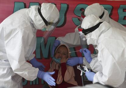 Health workers take a nasal swab sample from a girl during public testing for the new coronavirus conducted in Jakarta, Indonesia, Monday, June 15, 2020. (AP Photo/Achmad Ibrahim)