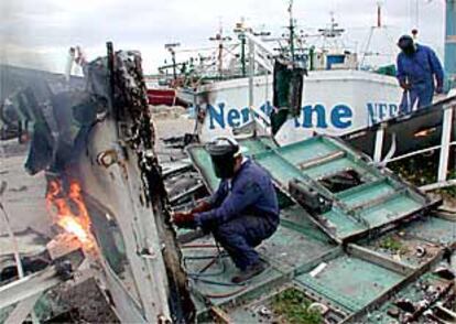 Dos trabajadores desguazan barcos pesqueros en el puerto andaluz de Barbate.