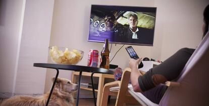 Una mujer viendo la televisión en su casa