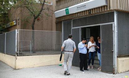 Varias personas a la puerta de una oficina de empleo, en el barrio de Amate, en Sevilla.