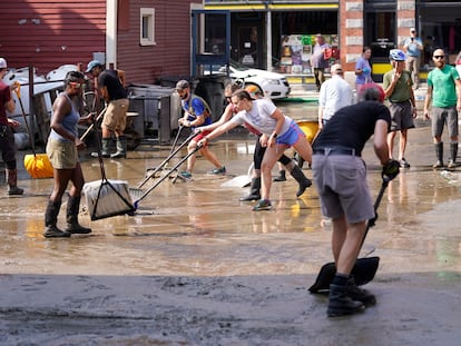 Volunteers clean up a downtown parking area on the banks of the Winooski River, Wednesday, July 12, 2023, in Montpelier, Vt.