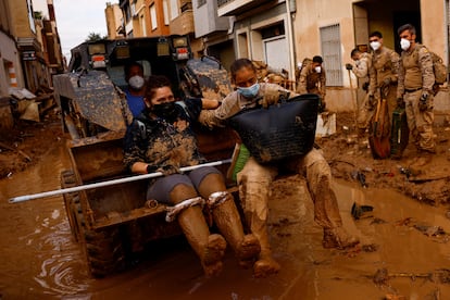 Susana Costa y un miembro del Ejército son trasladadas por una excavadora en Massanassa, este domingo.