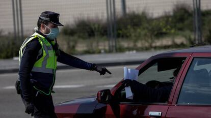 Un agente de la Policía Municipal pide a un conductor el justificante que le permite su salida de casa en un control policial de tráfico en Madrid. 