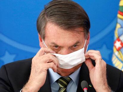 El presidente Bolsonaro se ajusta la mascarilla, durante un acto en Brasilia. / REUTERS