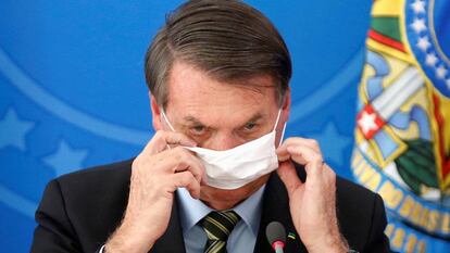 El presidente Bolsonaro se ajusta la mascarilla, durante un acto en Brasilia. / REUTERS