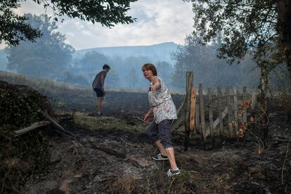 Una vecina de la localidad de Alixo llora al observar los daños causados por las llamas este lunes. Galicia vuelve a afrontar una jornada decisiva para extinguir los incendios forestales que afectan a las provincias de Ourense y Lugo y que mantienen en riesgo varios núcleos de población. 

