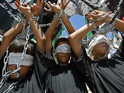 Tres niños con las manos encadenadas y haciendo el signo de la victoria, ayer en la manifestación en Gaza.