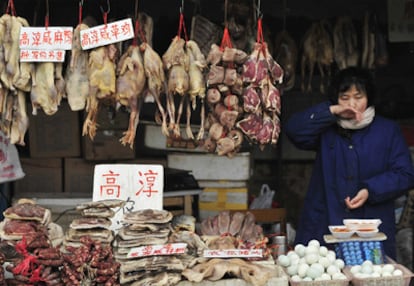 Una vendedora espera a los clientes en su puesto del mercado de aves y huevos de Nanjing.