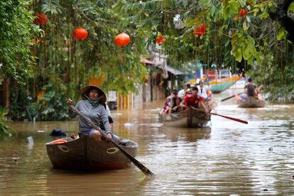 Varias personas navegan a bordo de sus embarcaciones a través de la localidad de Hoi An (Vietnam) inundada debido al tifón Damrey.