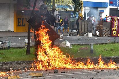 Um policial de choque é atingido por um coquetel molotov lançado durante confrontos com manifestantes.