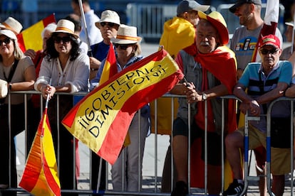 Bandera de España con el lema "¡¡Gobierno dimisión" es portada por uno de los asistentes a la convocatoria.