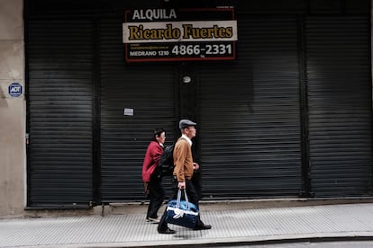 Una pareja camina junto a un antiguo local en renta, en Buenos Aires.