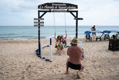 Russian tourists pose for a picture on a swing as they visit Punta Arenas beach during a guided tour in Isla Margarita, Nueva Esparta state, Venezuela, on November 24, 2022. - Russian tourists find a place to spend their holidays in political ally Venezuela. Since the beginning of the war and due to sanctions, there have been very few places Russians can visit. One of the remaining ones is the Caribbean island of Margarita. (Photo by Yuri CORTEZ / AFP)