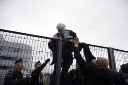 Pierre Plissonnier, amb el vestit i la camisa esquinçats, intenta saltar una tanca amb ajuda dels agents de seguretat després que centenars de treballadors hagin entrat a la seu d'Air France pel pla d'ajust.