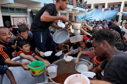 Población palestina recibe alimentos en una escuela administrada por la ONU enla ciudad de Rafah, al sur de la Franja de Gaza.  