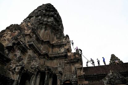 Ayudándose de una escalera contra las altísimas agujas de la maravilla arqueológica de Camboya, Angkor Wat, un equipo de jardineros escala el exterior del templo para cortar el follaje antes de que dañe la antigua fachada.