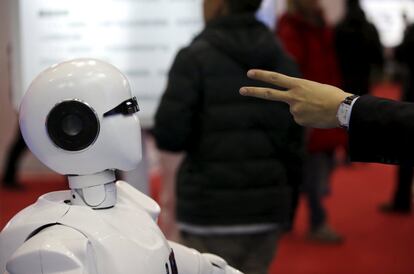 Un visitante gesticula ante un robot humanoide Kinger.