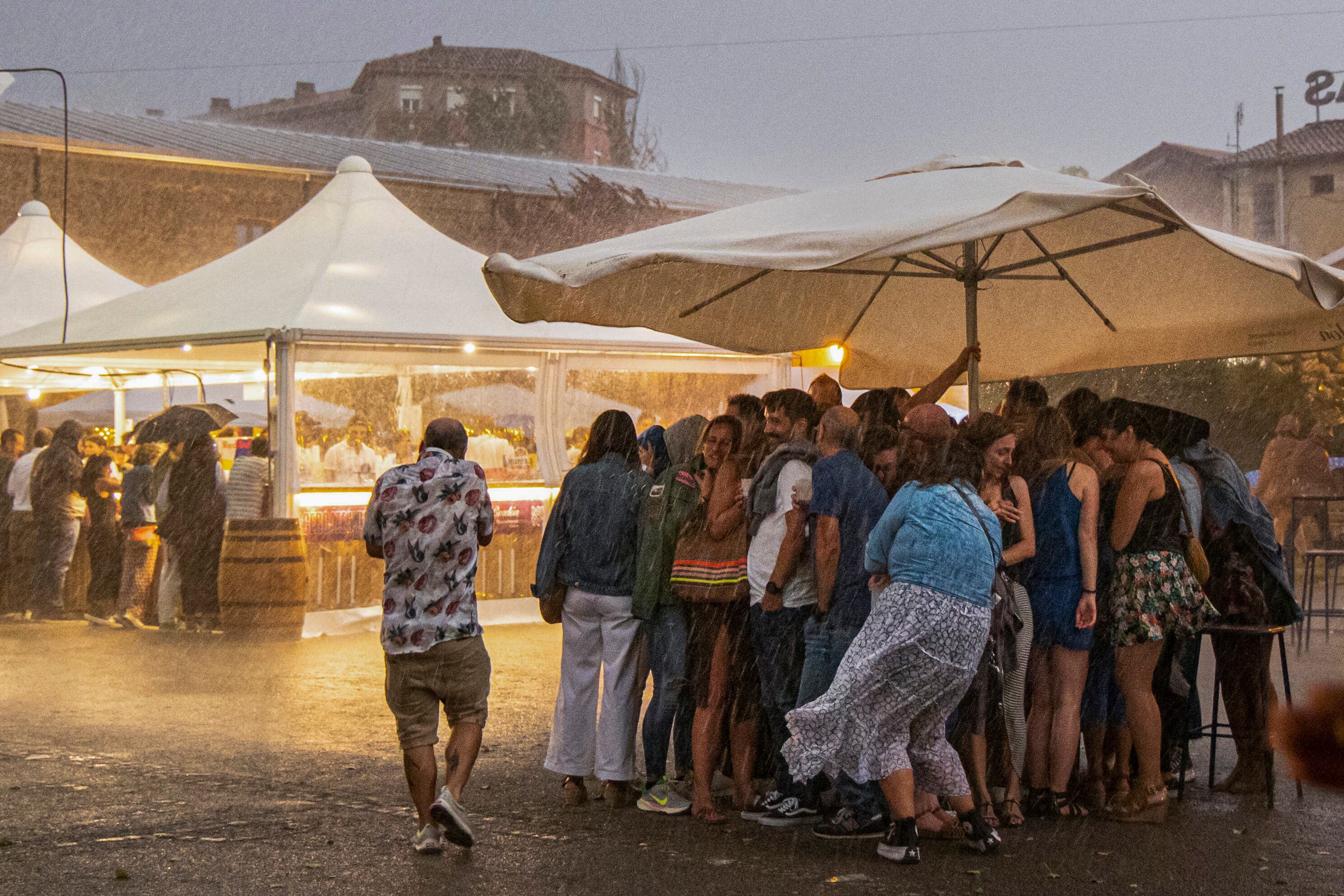 Varias personas se refugian de una tormena que ha descargado sobre Logroño en apenas cinco minutos y que ha obligado a poner fin al concierto de Quique González, en el festival Muwi, celebrado el viernes en las Bodegas Franco-Españolas de Logroño.