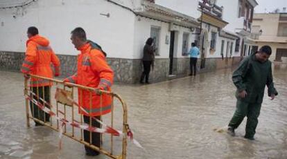 Dos operarios trasladan una valla en Zahara de los Atunes (Cádiz) tras la inundación.