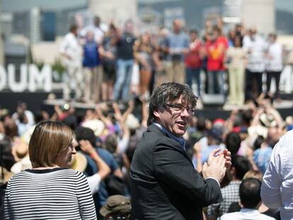 El presidente catalan, Carles Puigdemont (c), mira a la gente durante la lectura de un manifiesto independentista le&iacute;do por Josep Guardiola (al fondo).