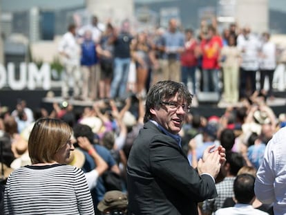 El presidente catalan, Carles Puigdemont (c), mira a la gente durante la lectura de un manifiesto independentista le&iacute;do por Josep Guardiola (al fondo).