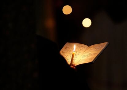 A Franciscan friar holds a candle during daily prayer in a chapel.