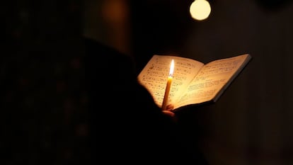 Un fraile franciscano sujeta una vela mientras reza y canta durante el rezo diario en una capilla.