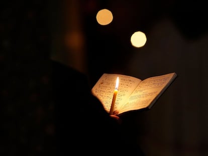 Un fraile franciscano sujeta una vela mientras reza y canta durante el rezo diario en una capilla.