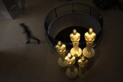 Un hombre camina junto a varias estatuas de los &#039;oscars&#039; en la entrada del Dolby Theatre.  