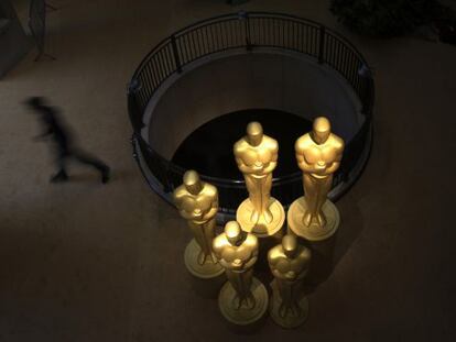 Un hombre camina junto a varias estatuas de los 'oscars' en la entrada del Dolby Theatre.