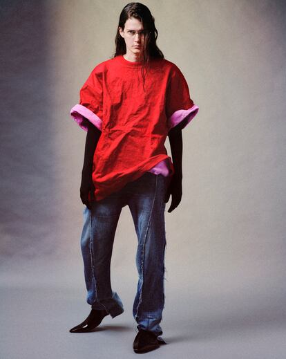 Eliza Douglas, con camiseta arrugada en jersey de aluminio rojo y rosa, jeans reciclados en denim azul claro, jersey negro con guantes incorporados de titanio y zapatos Space 2.0 en caucho brillante. 