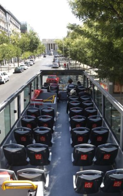 A near-empty tourist bus cruises the streets of Madrid during the summer.