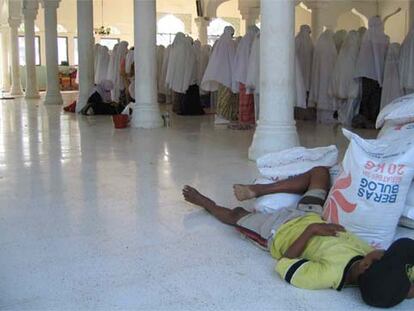 Un niño duerme junto a unos sacos de arroz en una mezquita de un campo de refugiados de Banda Aceh.