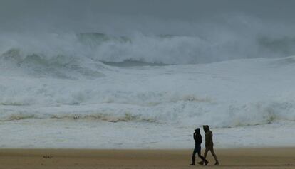 Una pareja pasea por Praia do Norte, en Nazar&eacute; (Portugal). 