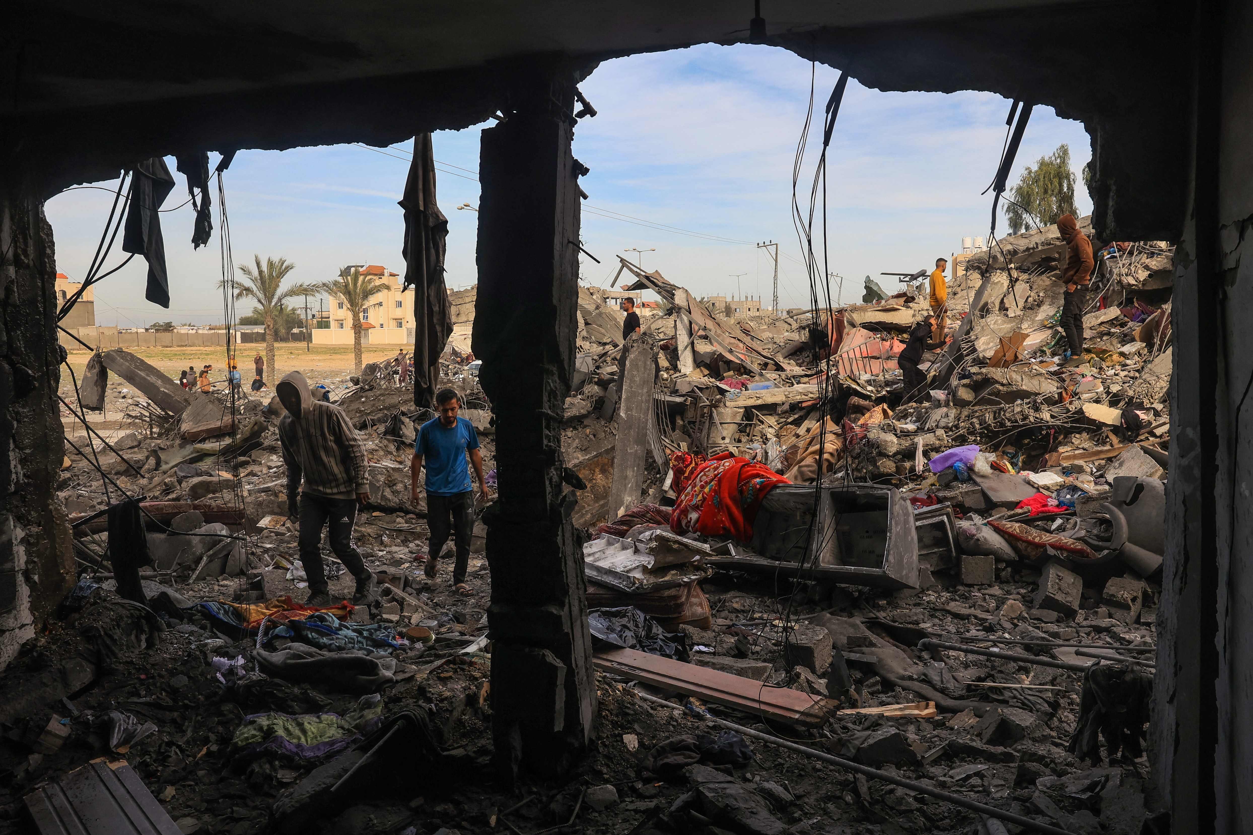 Varios hombres andan entre los escombros de un edificio derruido tras un bombardeo israelí al sur de la franja de Gaza.  