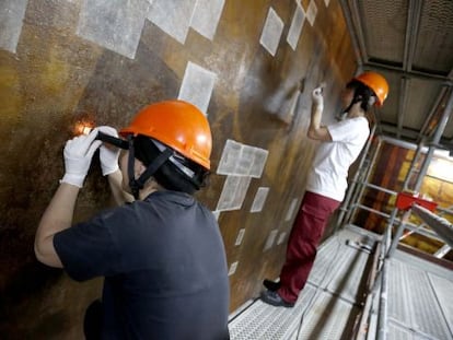 Dos restauradores trabajan sobre los lienzos de Sert, que decoran la iglesia del Museo San Telmo.