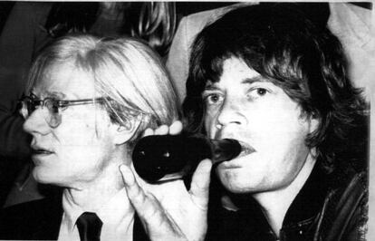 El líder de los " Rolling Stones" , Mick Jagger, bebe un refresco en compañía del artista Andy Warhol ( izda) , durante la promoción de su nuevo disco ' Love You Live' en 1977.