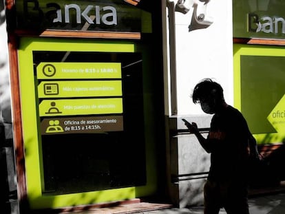 Una persona camina por el centro de Madrid delante de una sucursal de Bankia.