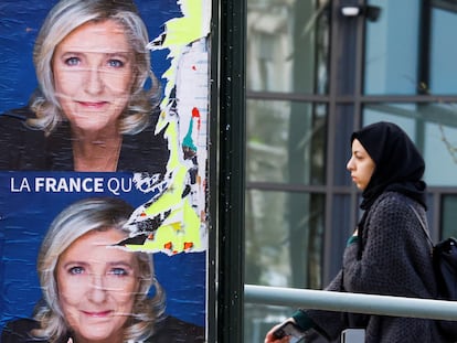 Una mujer pasa junto a unos carteles electorales que piden el voto para Marine Le Pen.