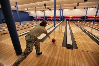 Una soldado juega en la bolera en la base naval de Guantánamo. Algunas personas llevan bolsas de diseño militar para transportar sus bolos. La bolera está al lado de un gimnasio y de un campo de fútbol americano.