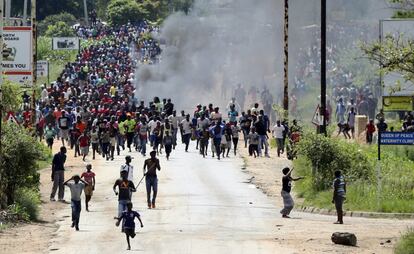 Una multitud de manifestantes corre durante los enfrentamientos con la policía mientras trata de bloquear algunas carreteras de Harare.