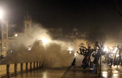 Varias personas, sorprendidas por las olas en el paseo de la Concha en la noche del sábado.