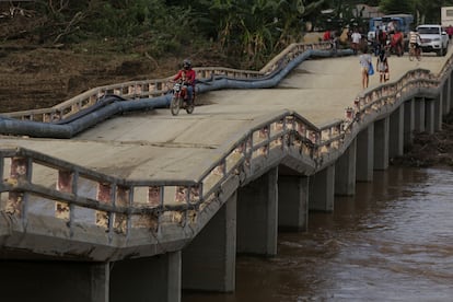 Personas cruzan un puente afectado por el huracán Oscar en la provincia de Guantánamo, al oriente de Cuba.