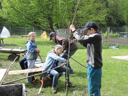 Ni&ntilde;os suizos cortando ramas en un parque de aventura.