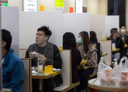 Em um restaurante em Hong Kong as mesas são divididas com uma tela de plástico.