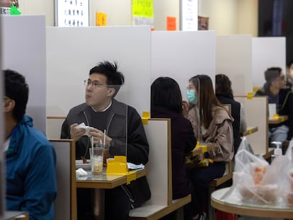 Em um restaurante em Hong Kong as mesas são divididas com uma tela de plástico.